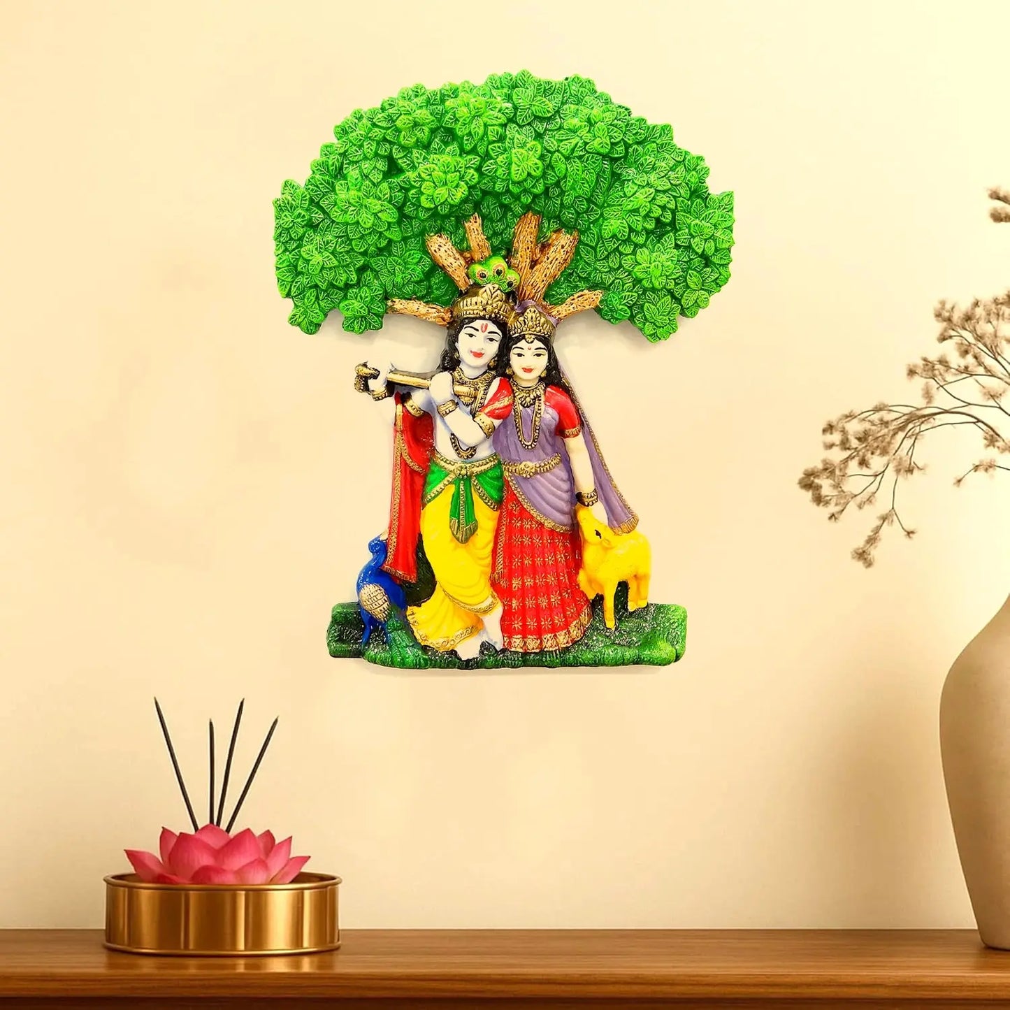 Decorative statue of two figures under a tree on a beige wall with a wooden shelf.