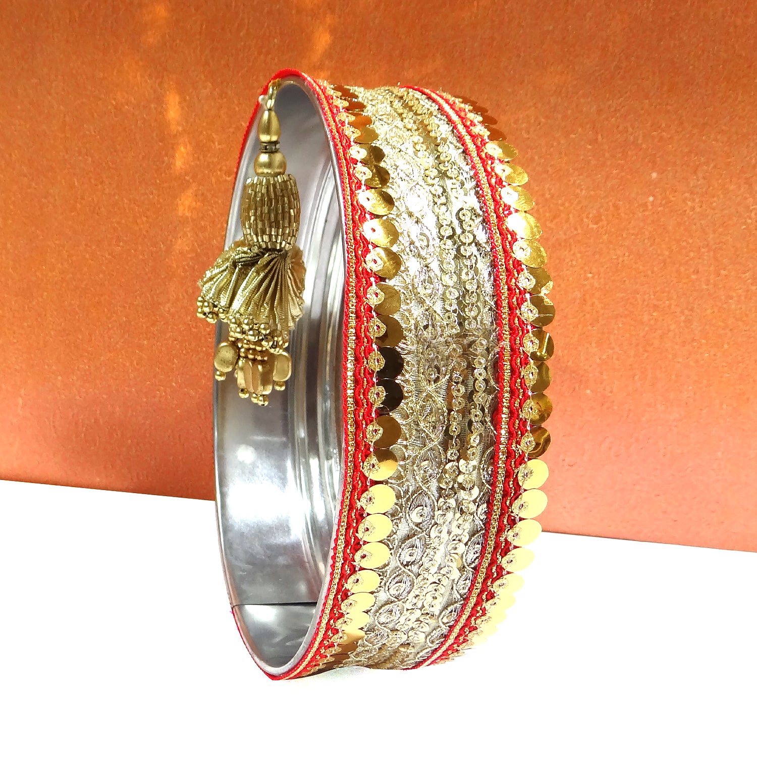 Decorative bangle with gold and red details on an orange background