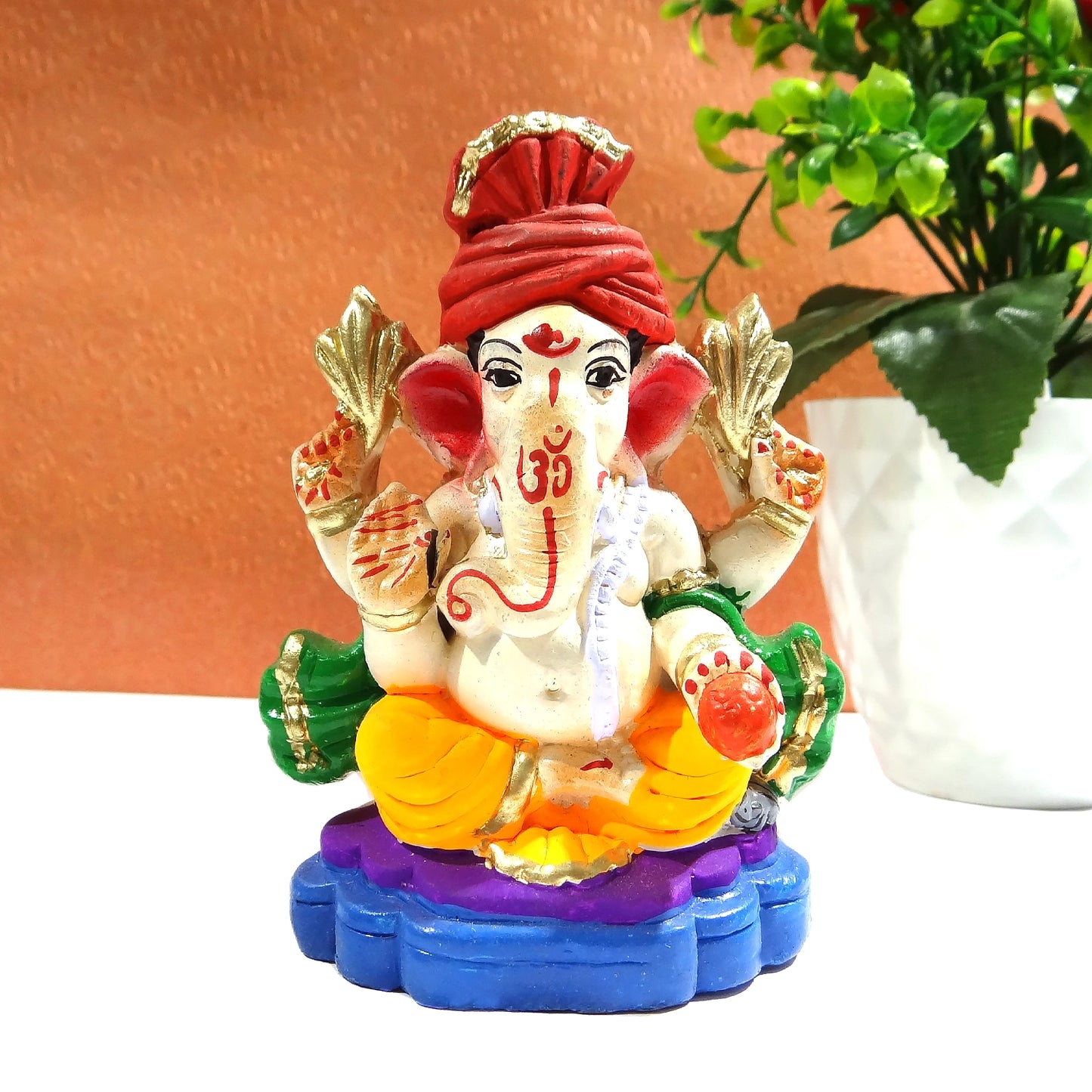 Colorful figurine of a deity with a red turban on a white surface.