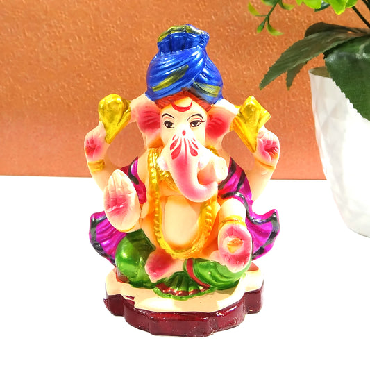 Colorful statue of a deity with a blue turban on a white surface.