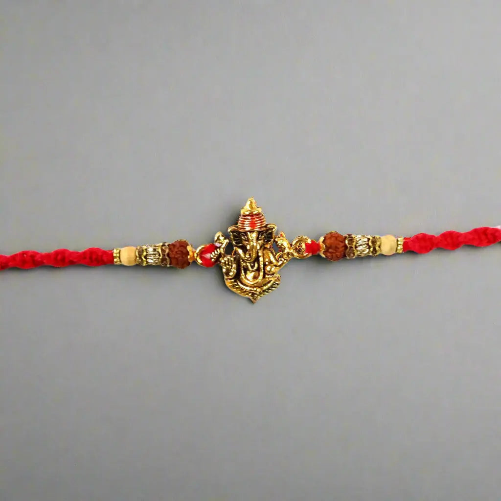 Bracelet with red cord, gold and red beads, and a decorative element on a gray background