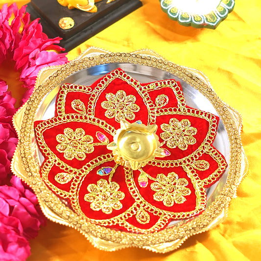 Decorative thali with red and gold design on a yellow fabric background