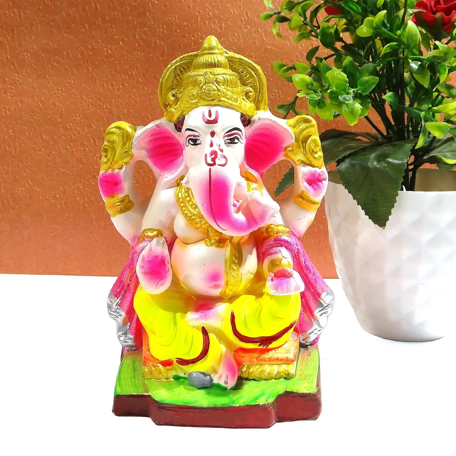 Colorful Ganesha statue with a plant in the background