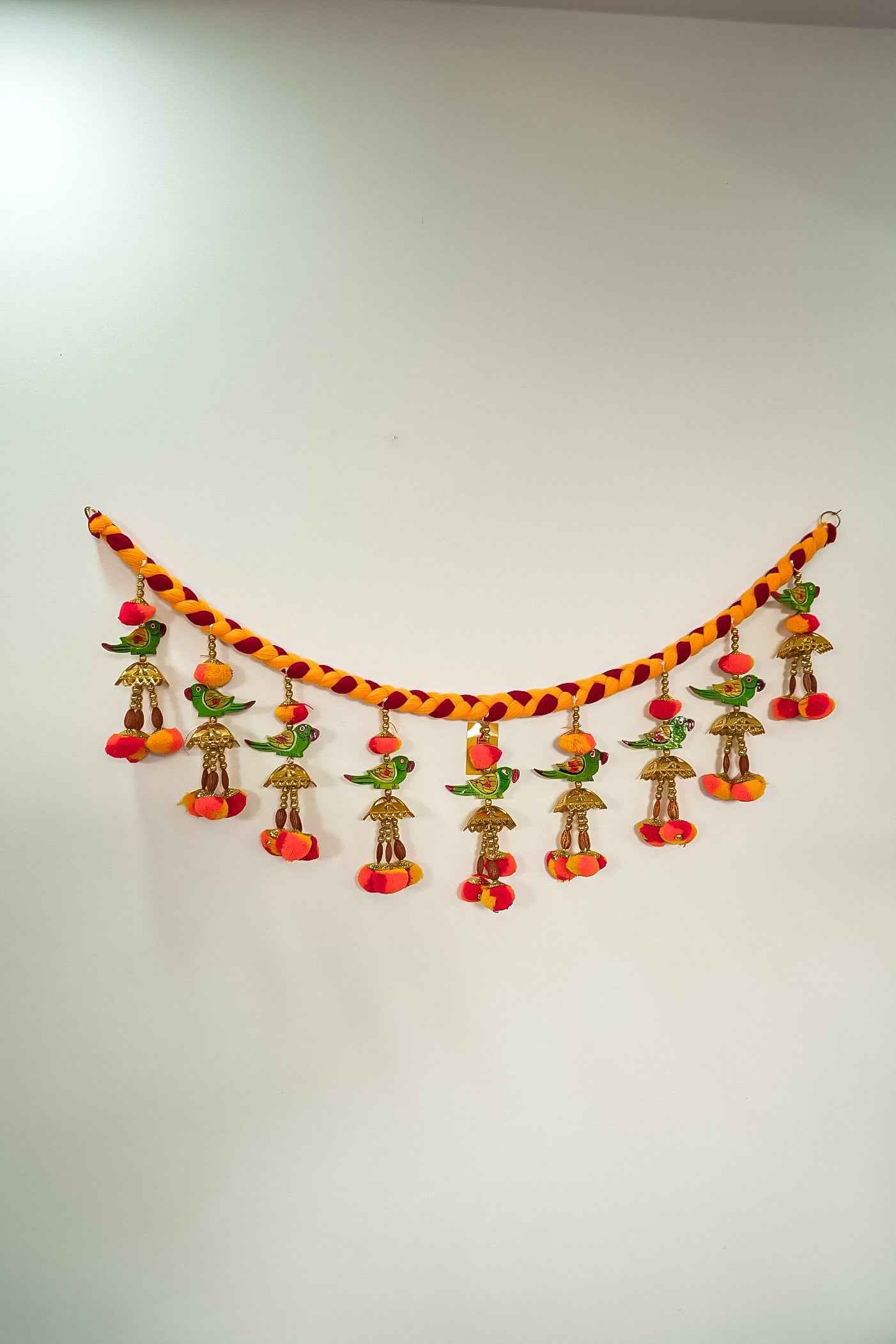 A Handcrafted Door Parrot Hanging Bandhanwar with parrot figurines, colorful beads, and ghungroos against a vibrant thread background.