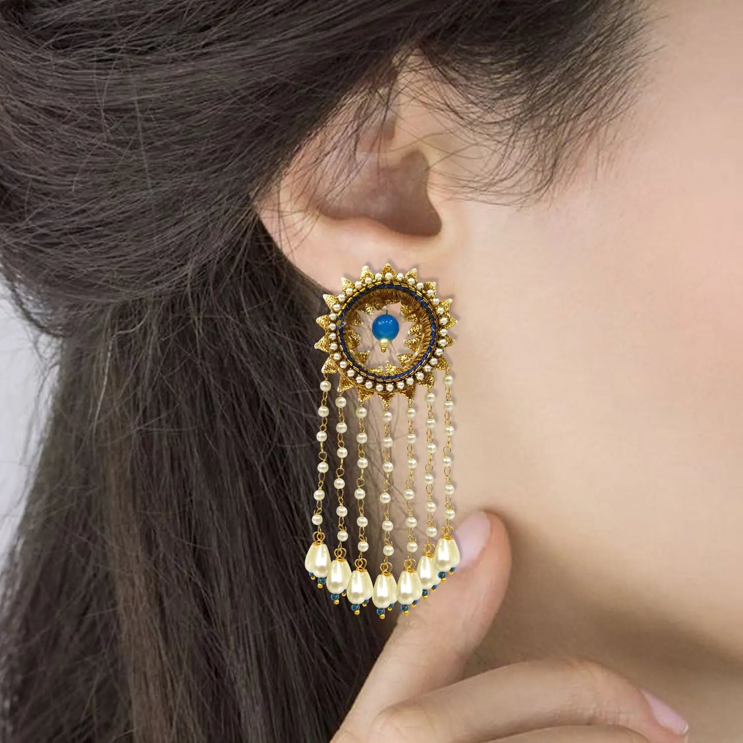 Close-up of a person wearing a decorative earring with beads and a blue gemstone.