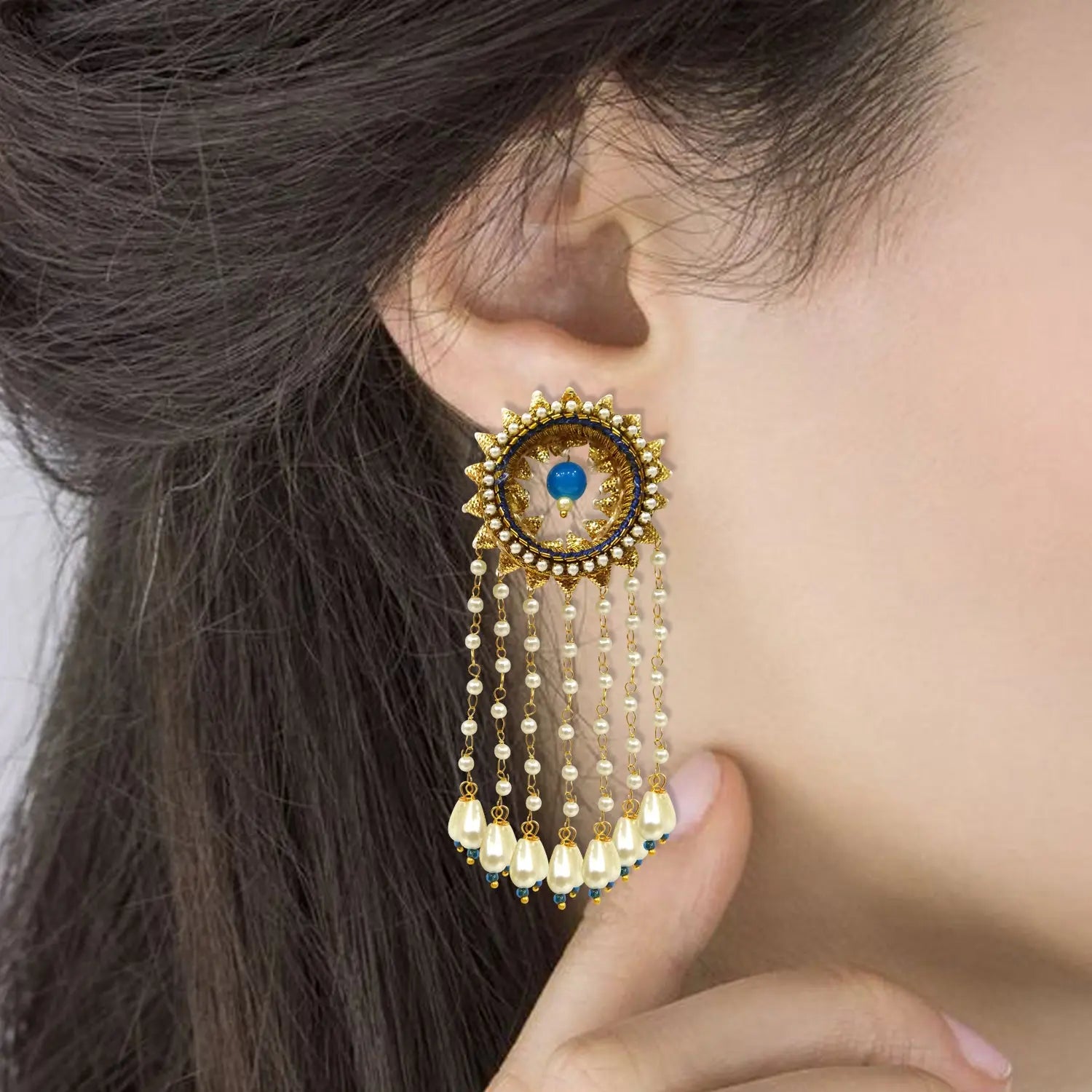 Close-up of a person wearing a decorative earring with beads and a blue gemstone.