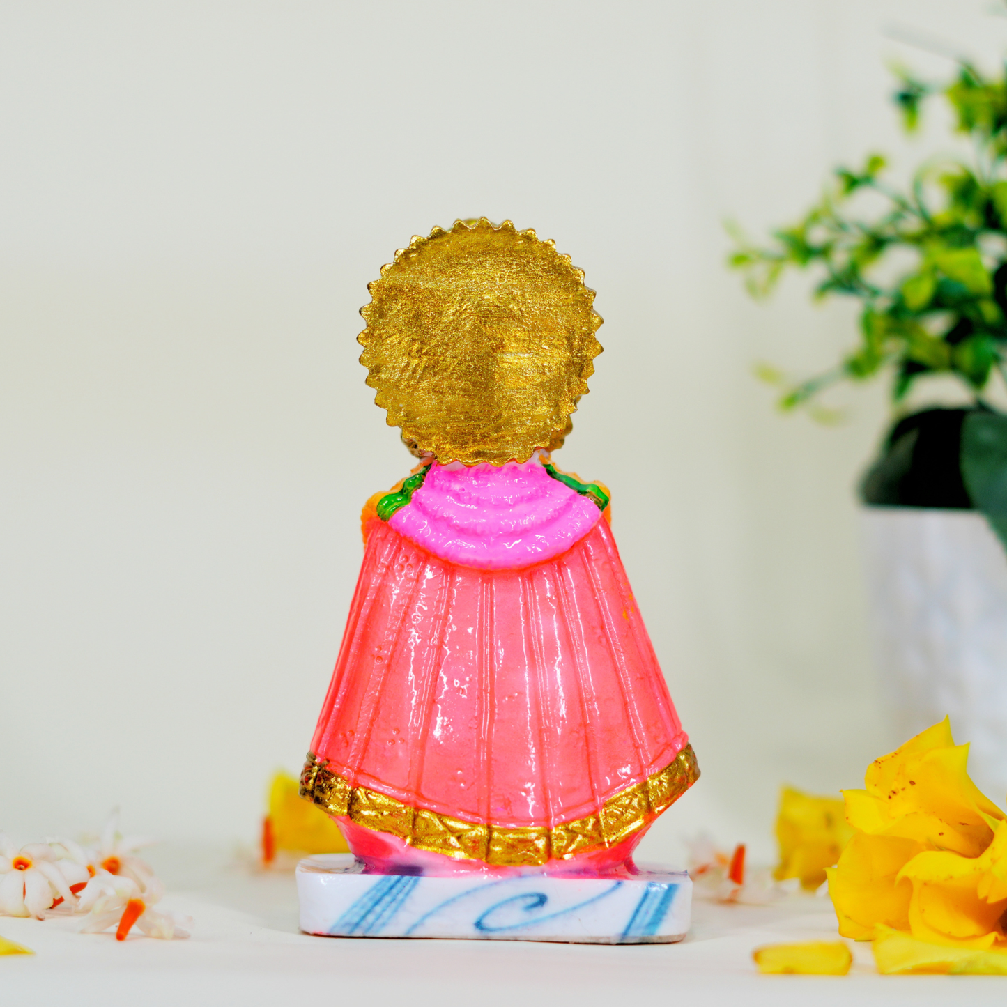 Decorative figurine with gold hair and pink outfit on a white surface with flowers.