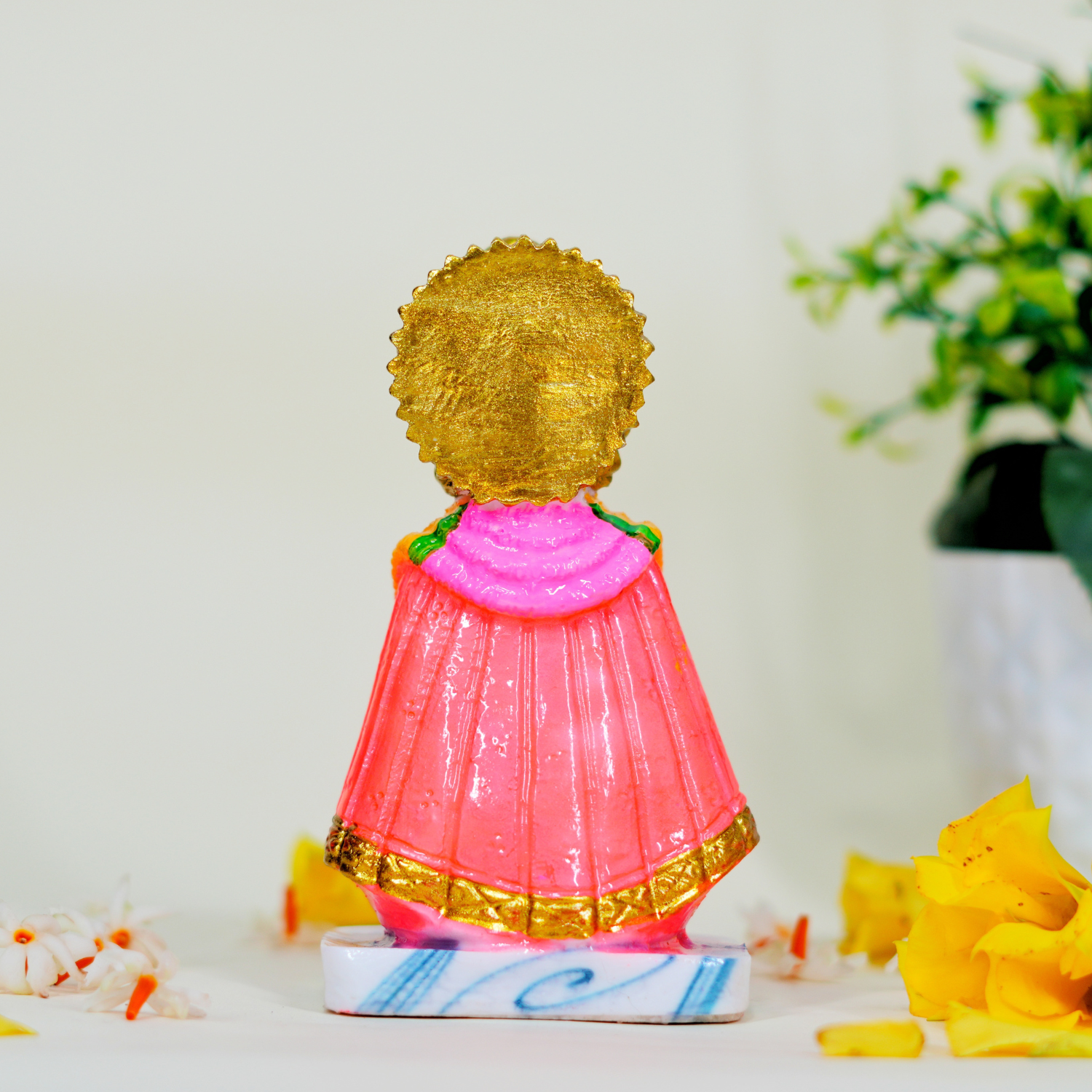 Decorative figurine with gold hair and pink outfit on a white surface with flowers.