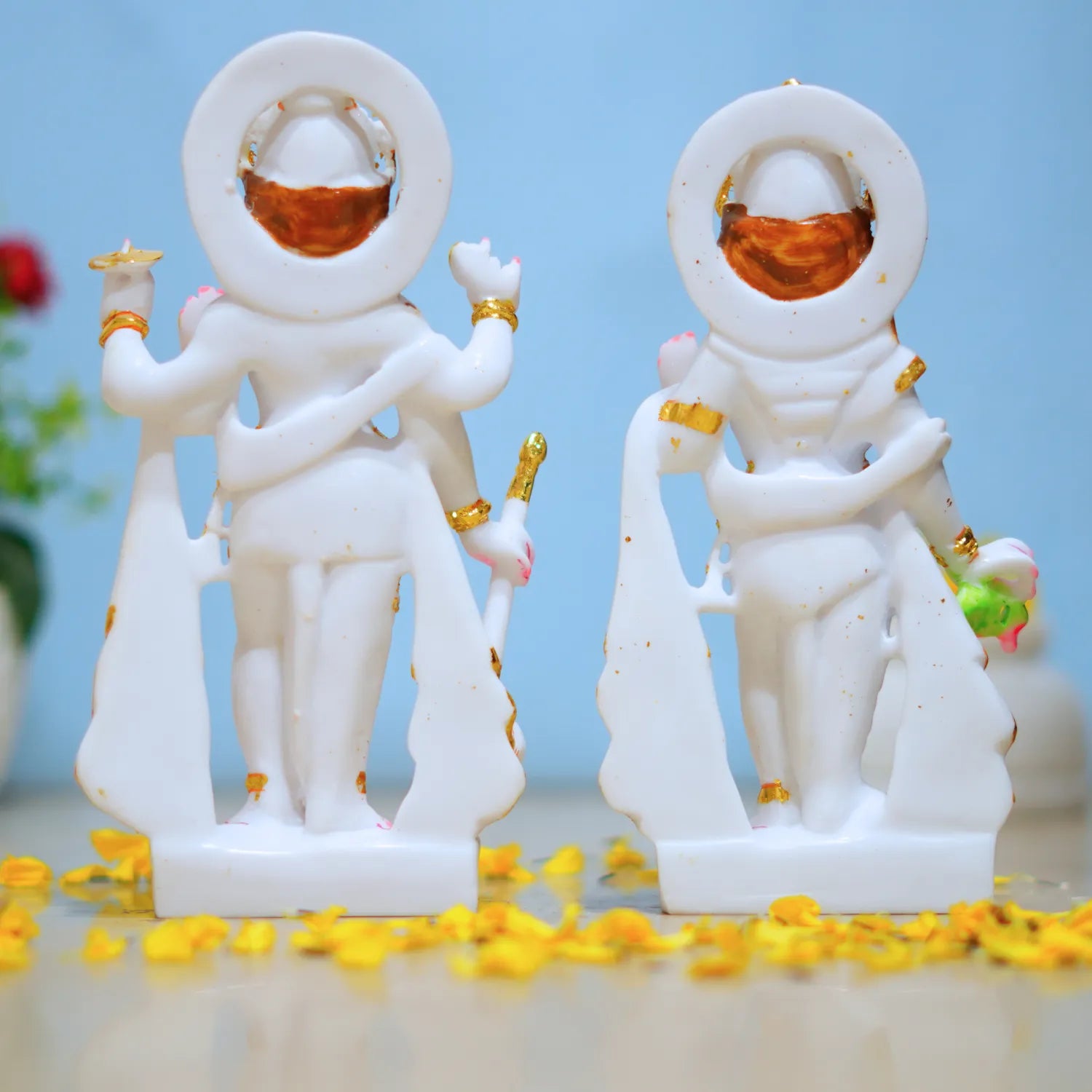 Two white figurines with gold accents on a light blue background