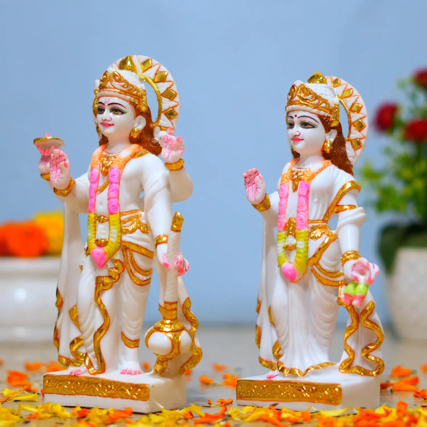 Two ornate statues with gold and pink details on a light blue background.