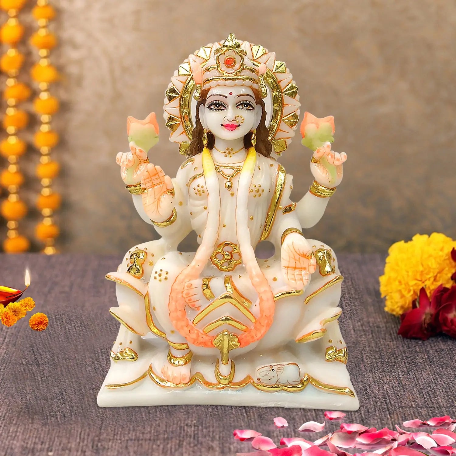 Decorative statue of a deity with flowers and lights in the background