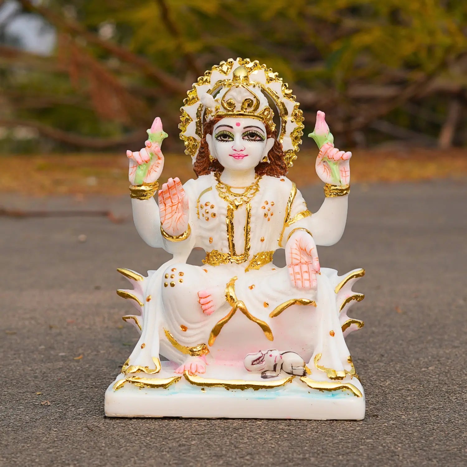 Decorative statue of a seated figure with gold and white attire on a dark surface.