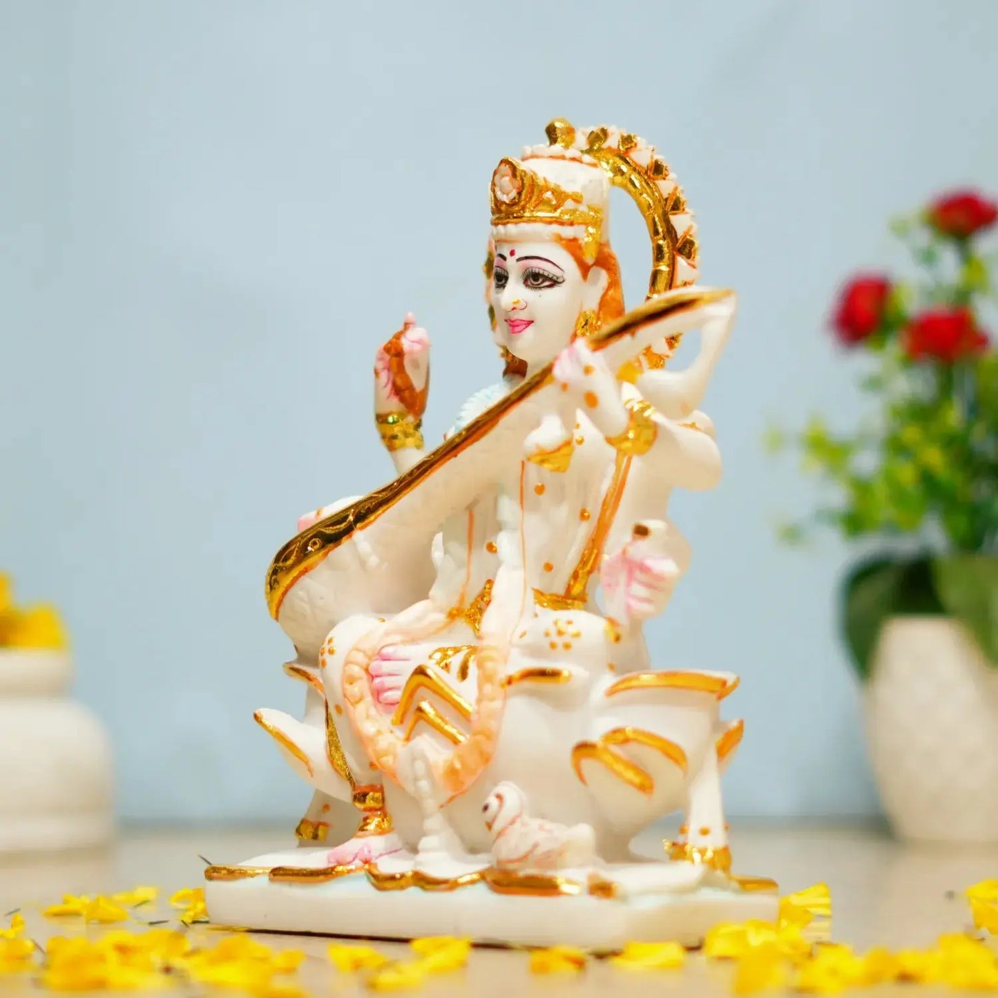 Decorative statue of a deity with gold accents on a light blue background