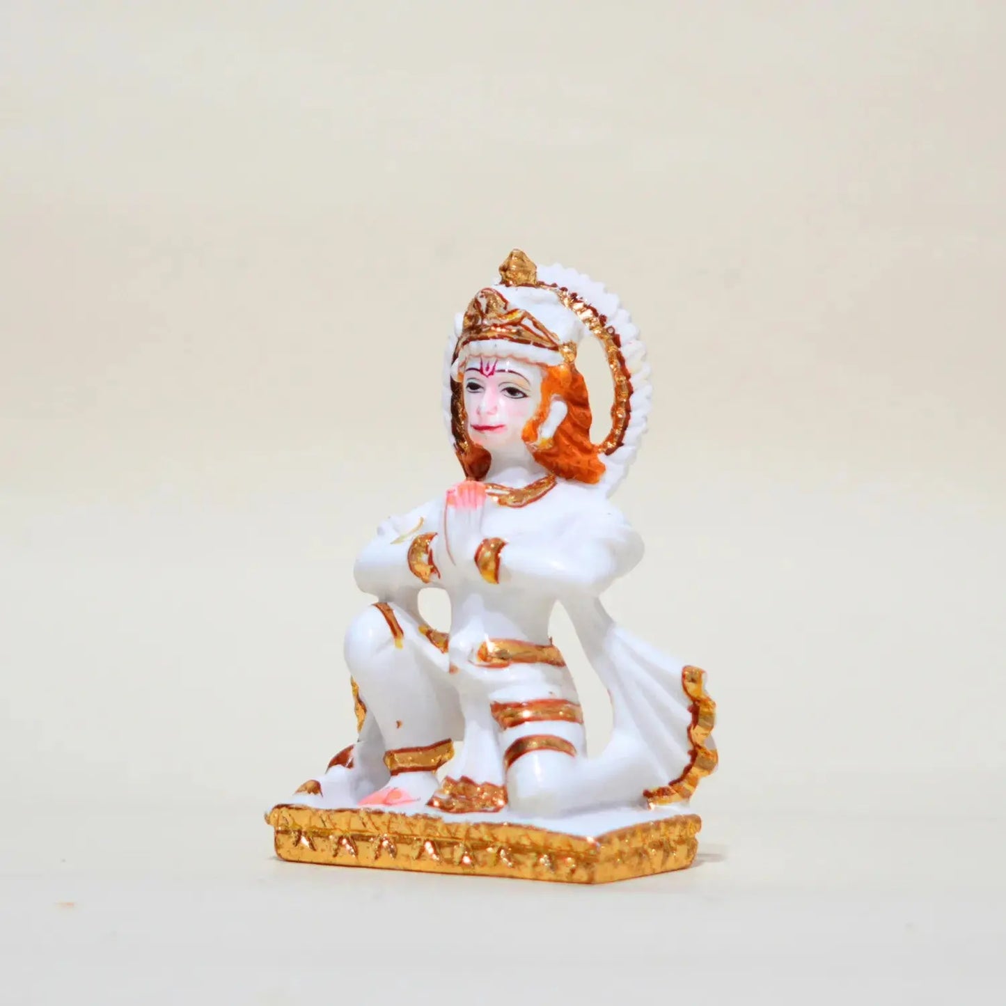 Decorative statue of a seated figure with white and gold attire on a beige background