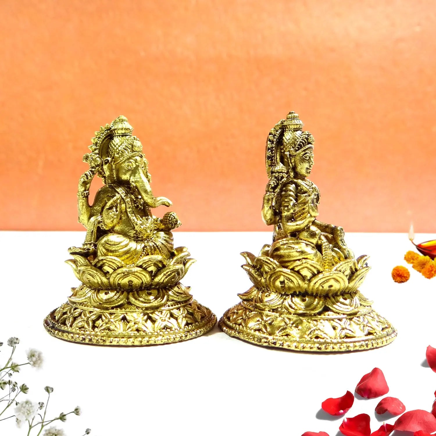 Two gold-colored statues on a white surface with an orange background