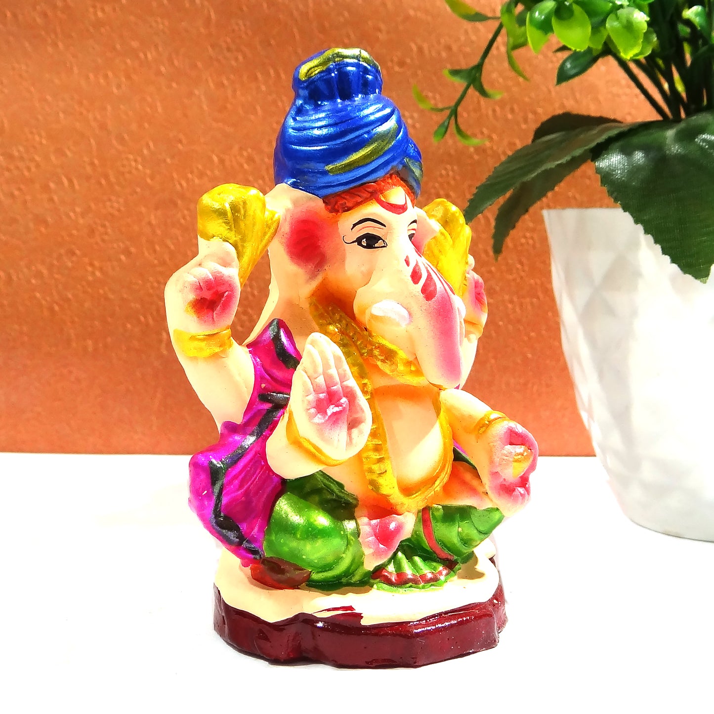Colorful statue of a deity with a blue turban on a white surface.