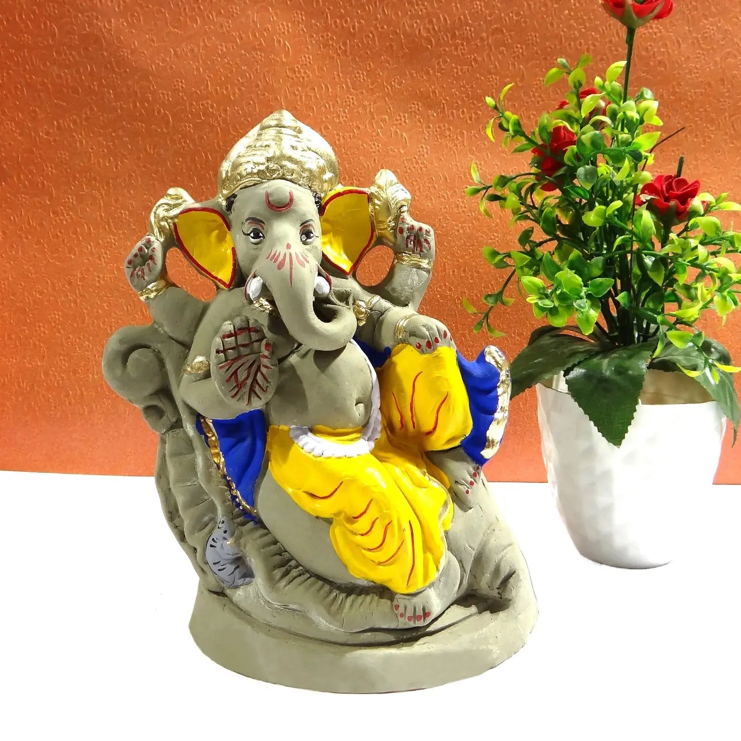 Colorful statue of a deity with a plant on an orange background