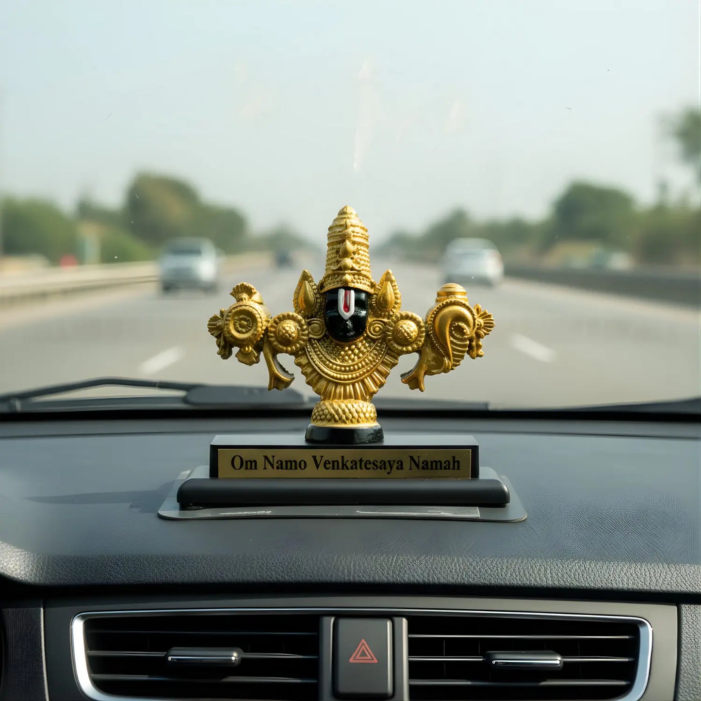 Decorative figurine on a car dashboard with a blurred highway background
