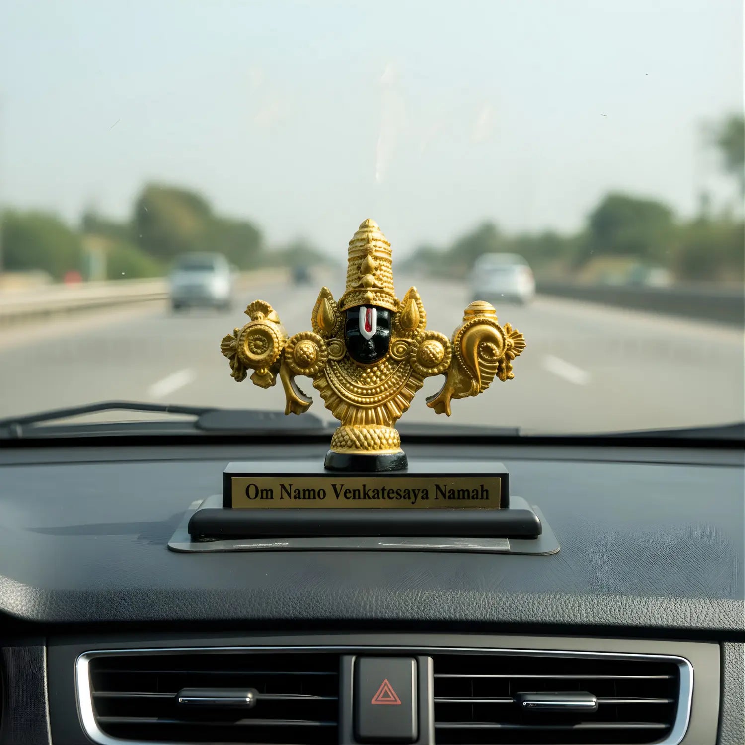 Decorative figurine on a car dashboard with a blurred highway background