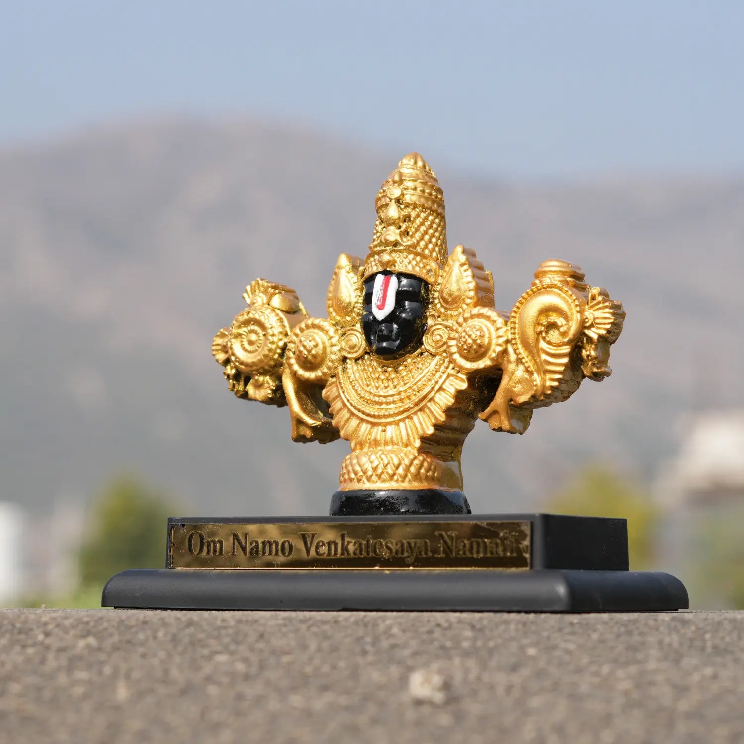 Decorative statue with gold and black details on a blurred natural background