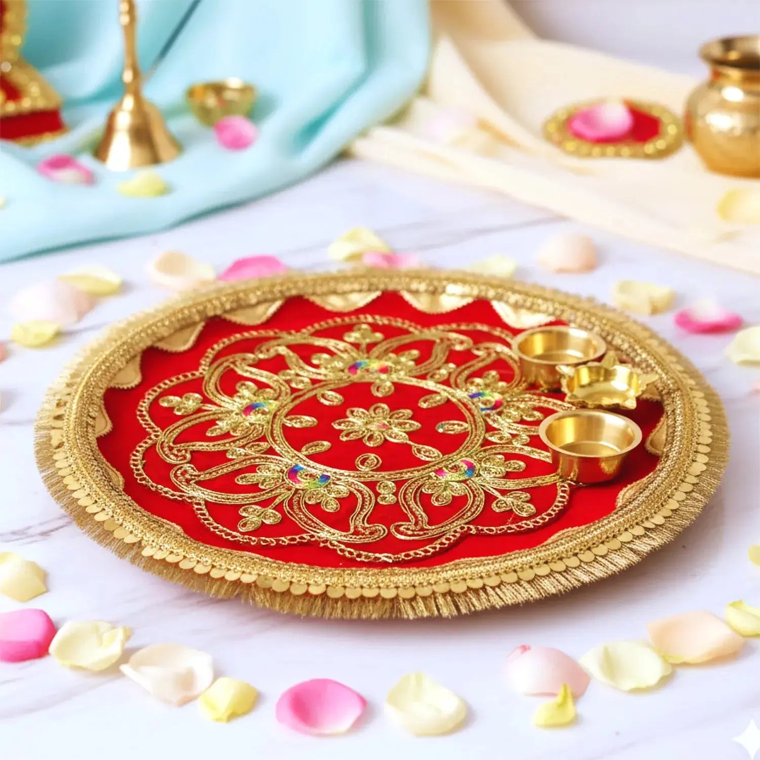 Decorative red and gold plate with small cups on a white surface with flower petals.