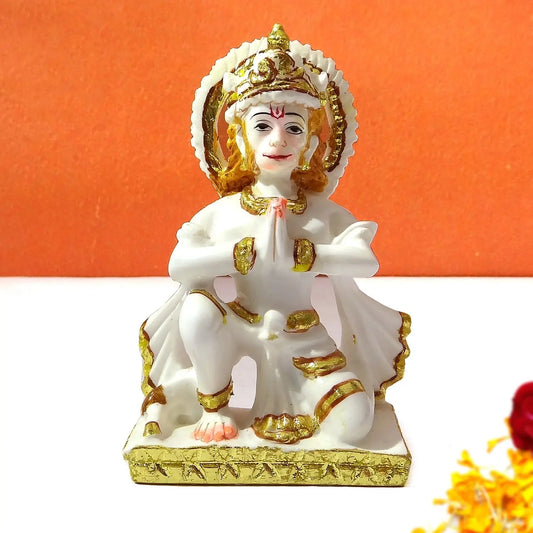 White and gold statue of a seated figure on an orange background