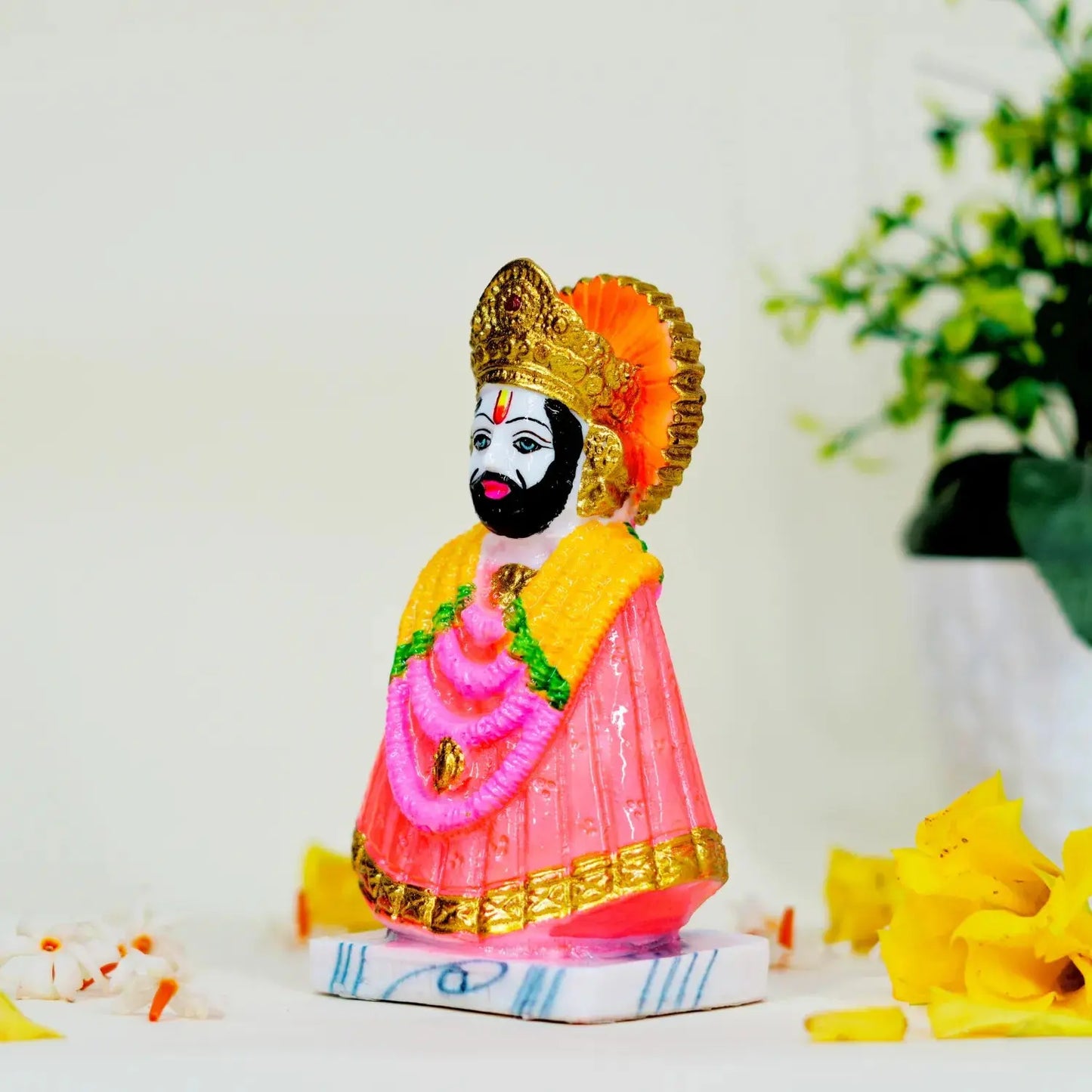 Colorful figurine of a deity with a white background and decorative elements.