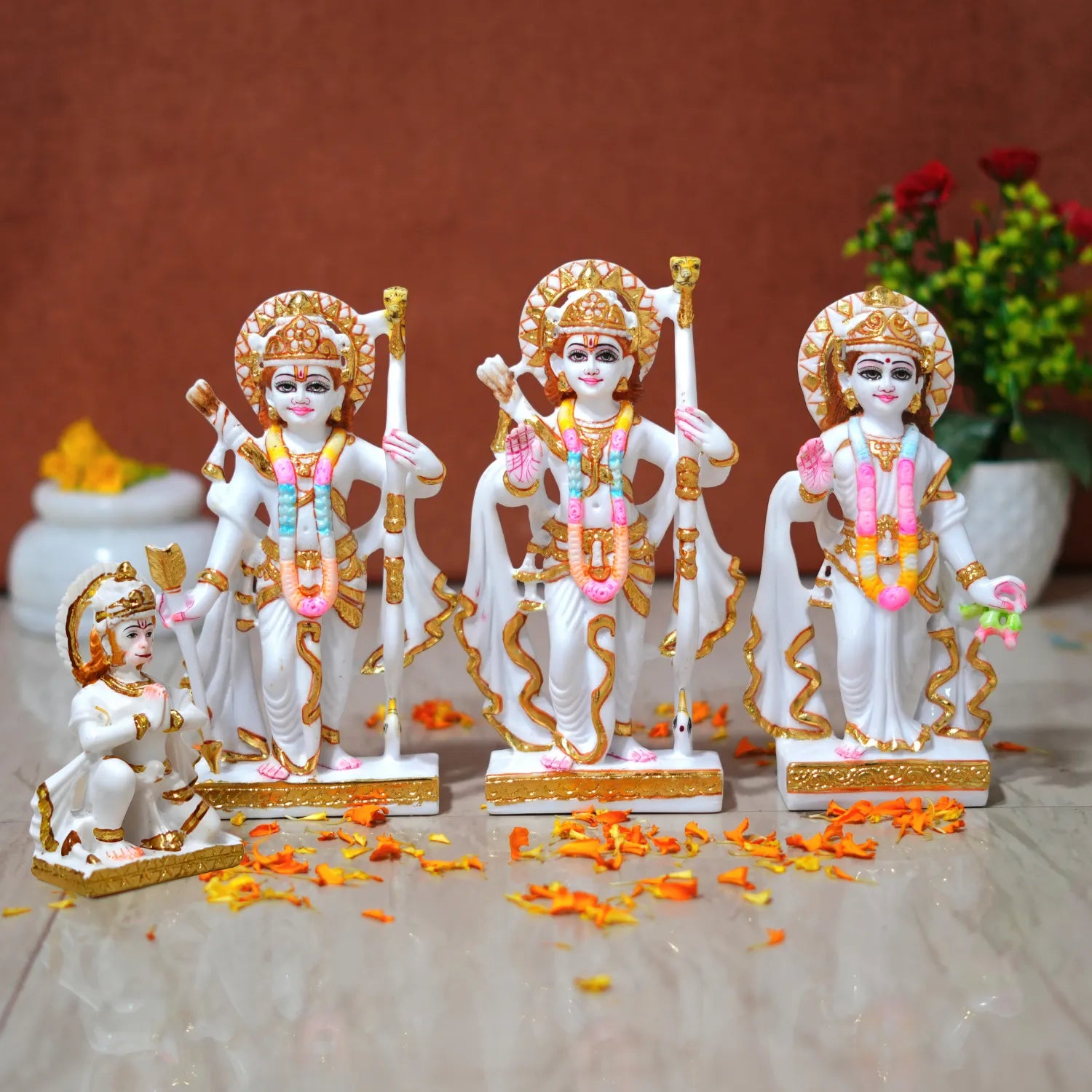 Set of four decorative statues with gold and white details on a brown surface.