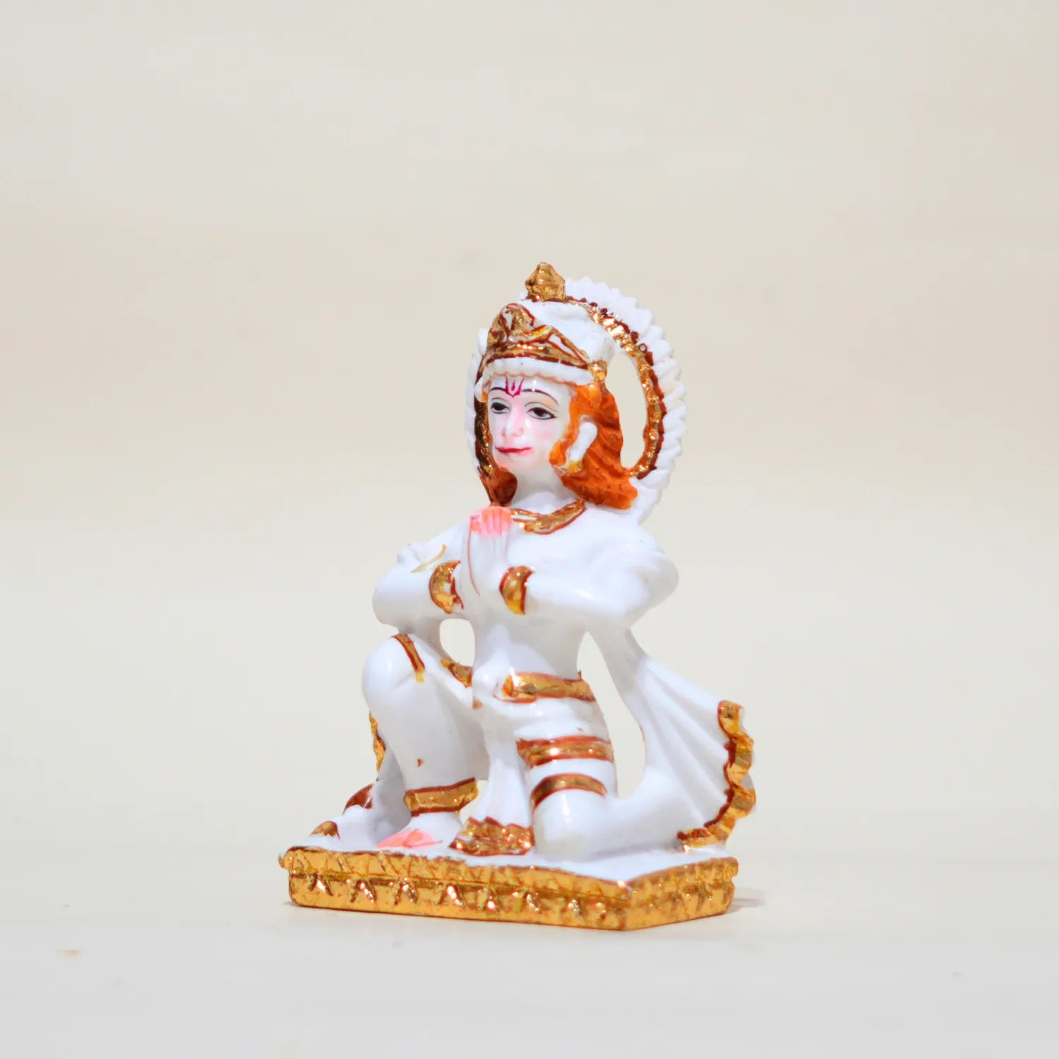 Decorative statue of a seated figure with white and gold attire on a beige background