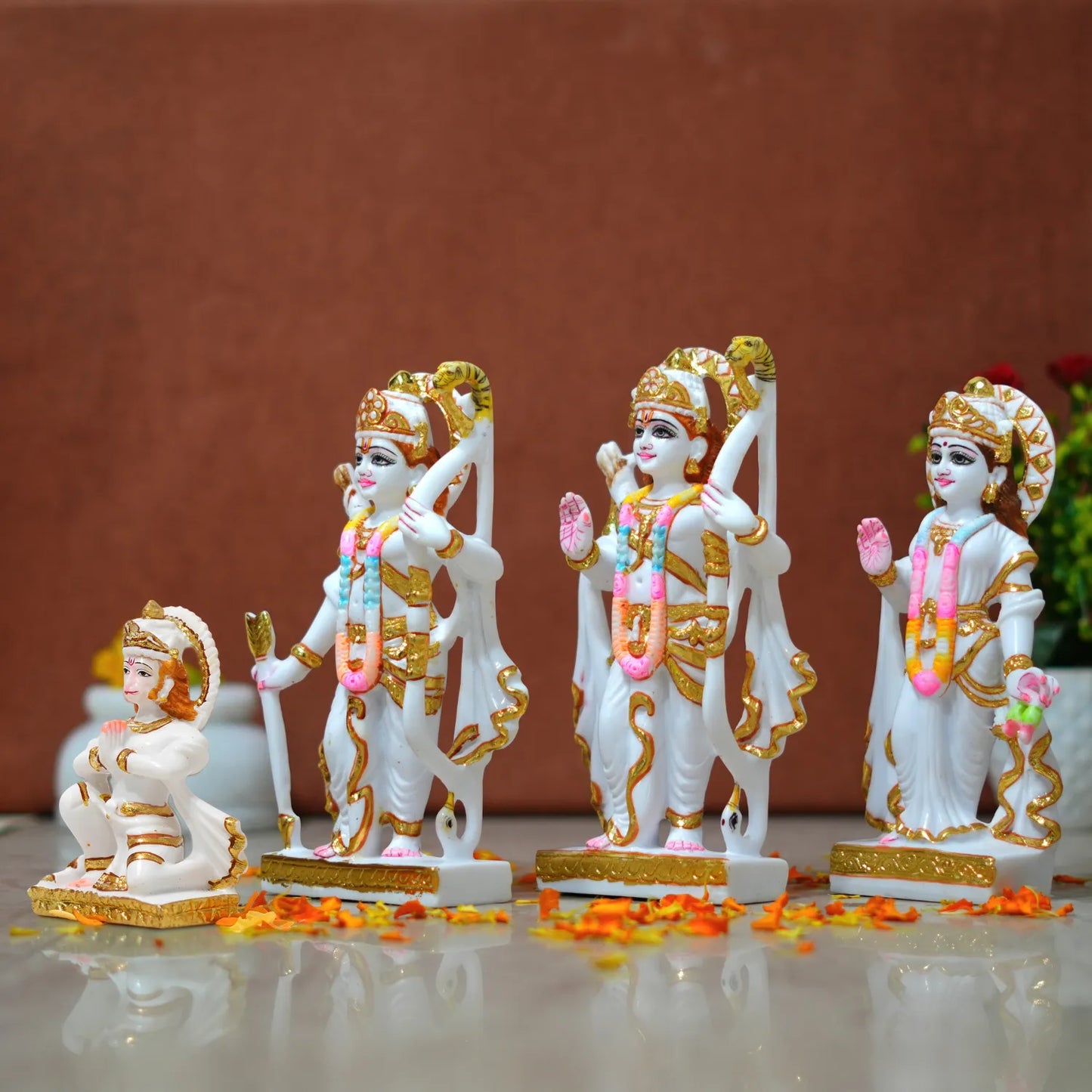 Set of five decorative statues with gold and white details on a reflective surface.