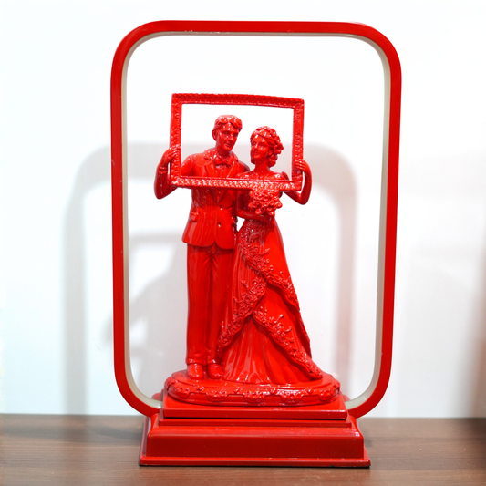 Red statue of a couple holding a frame on a white background