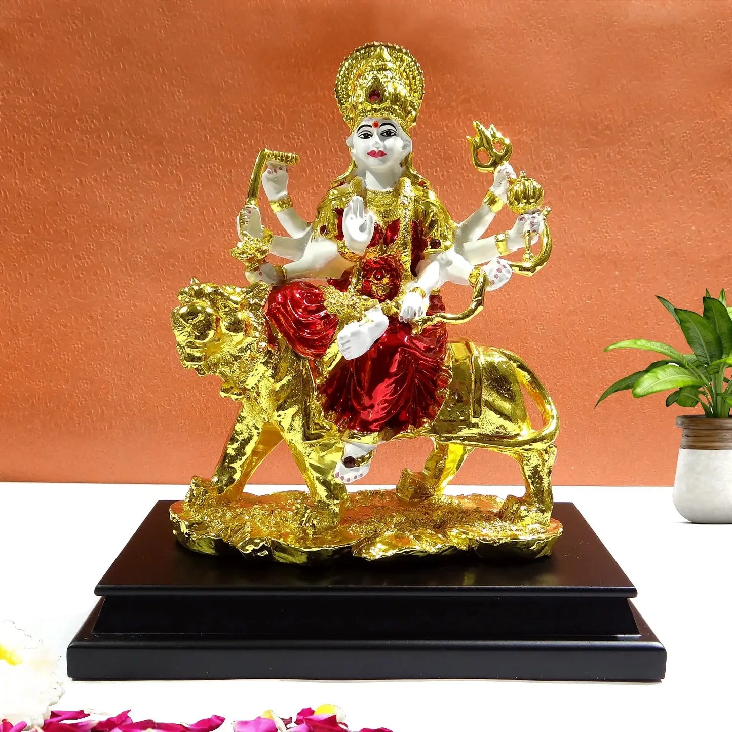 Decorative statue of a deity on a lion with gold and red colors on a white background