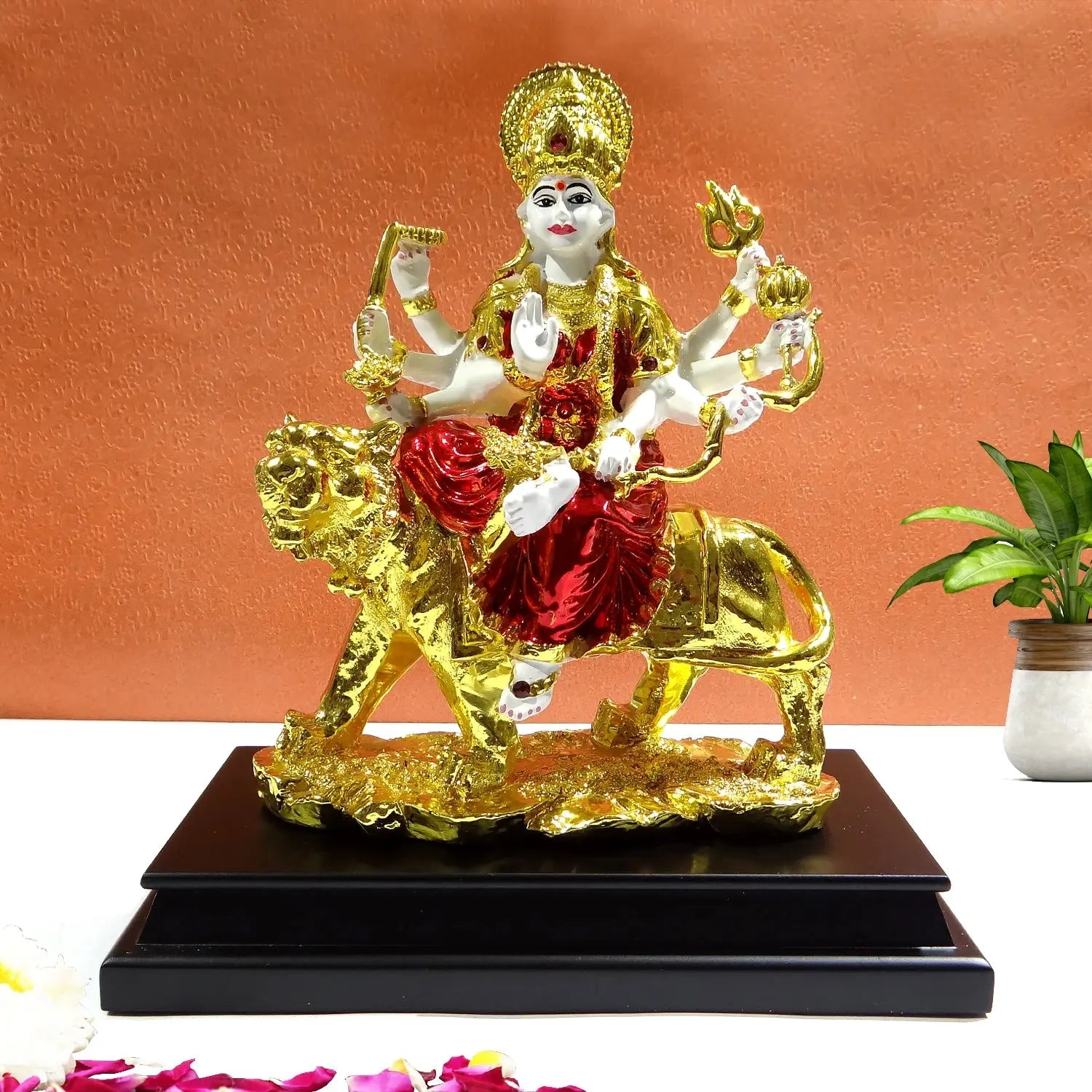 Decorative statue of a deity on a lion with gold and red colors on a white background