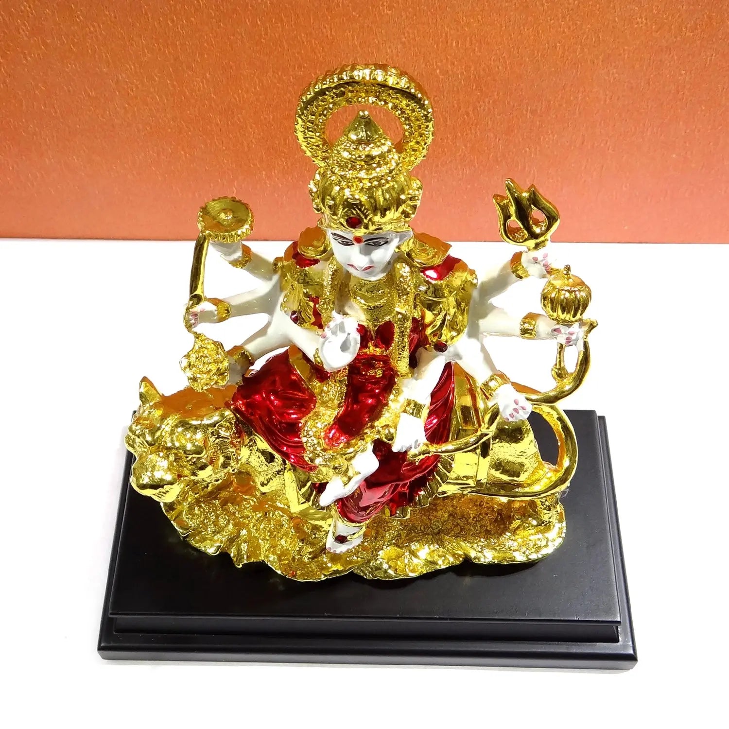 Decorative statue of a deity on a black base with an orange background