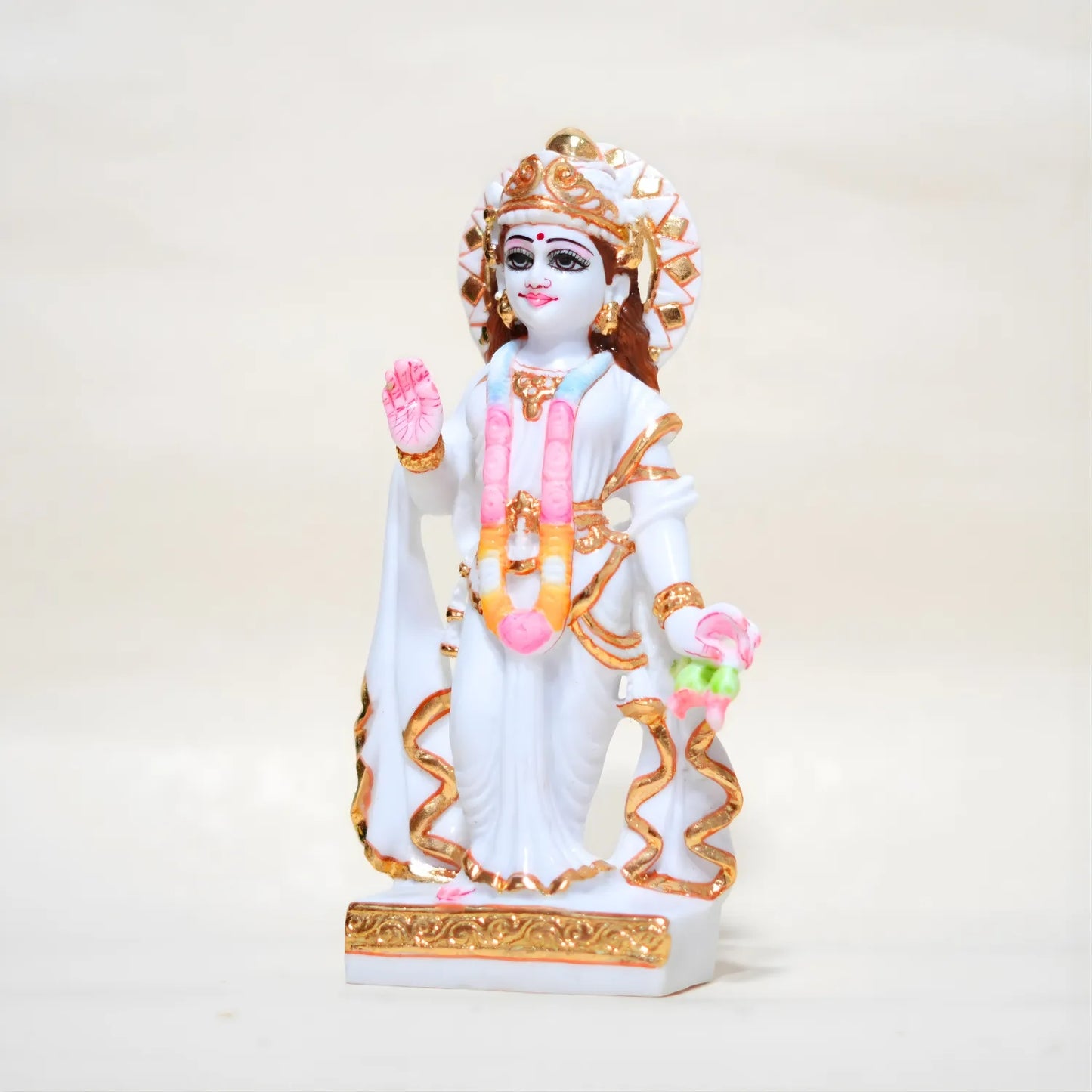 Statue of a deity with white and gold attire on a light beige background