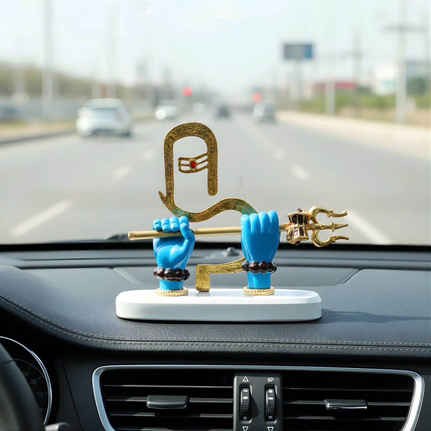 Decorative figure on a car dashboard with a blurred road background