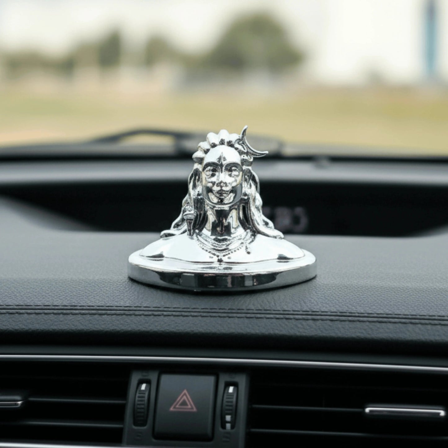 Car dashboard with a decorative figure on a blurred outdoor background