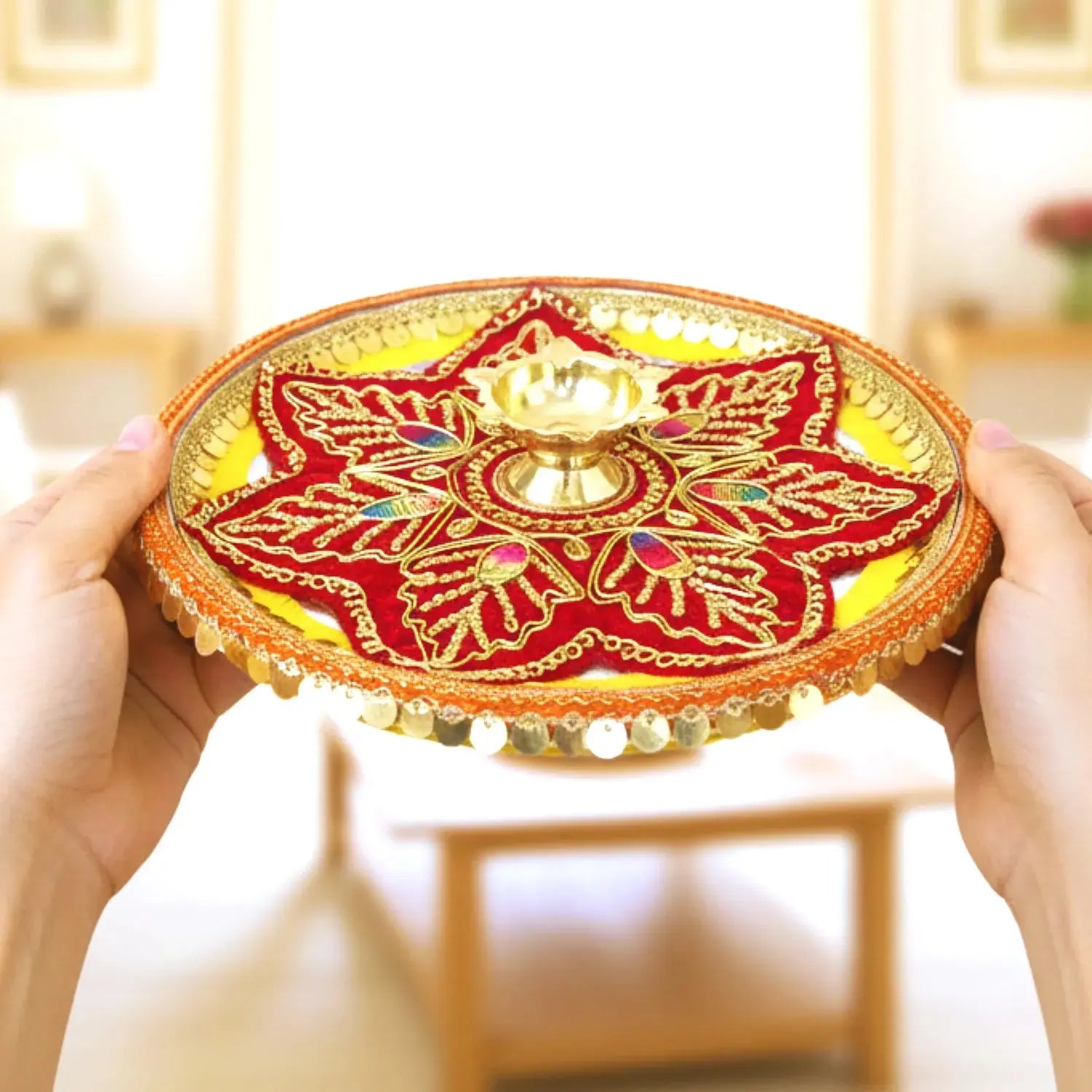 Decorative red and gold plate held by hands in a blurred indoor setting
