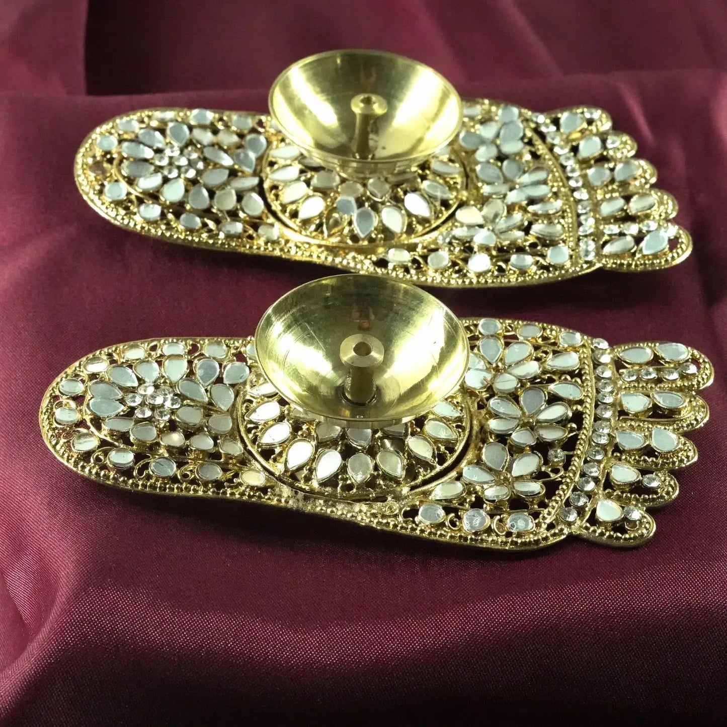 Two ornate gold and pearl decorative pieces on a purple fabric background