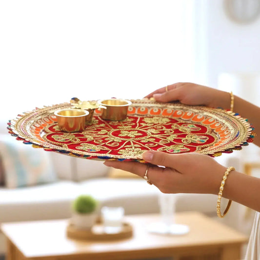Decorative tray with gold and red design held by a person in a living room setting.