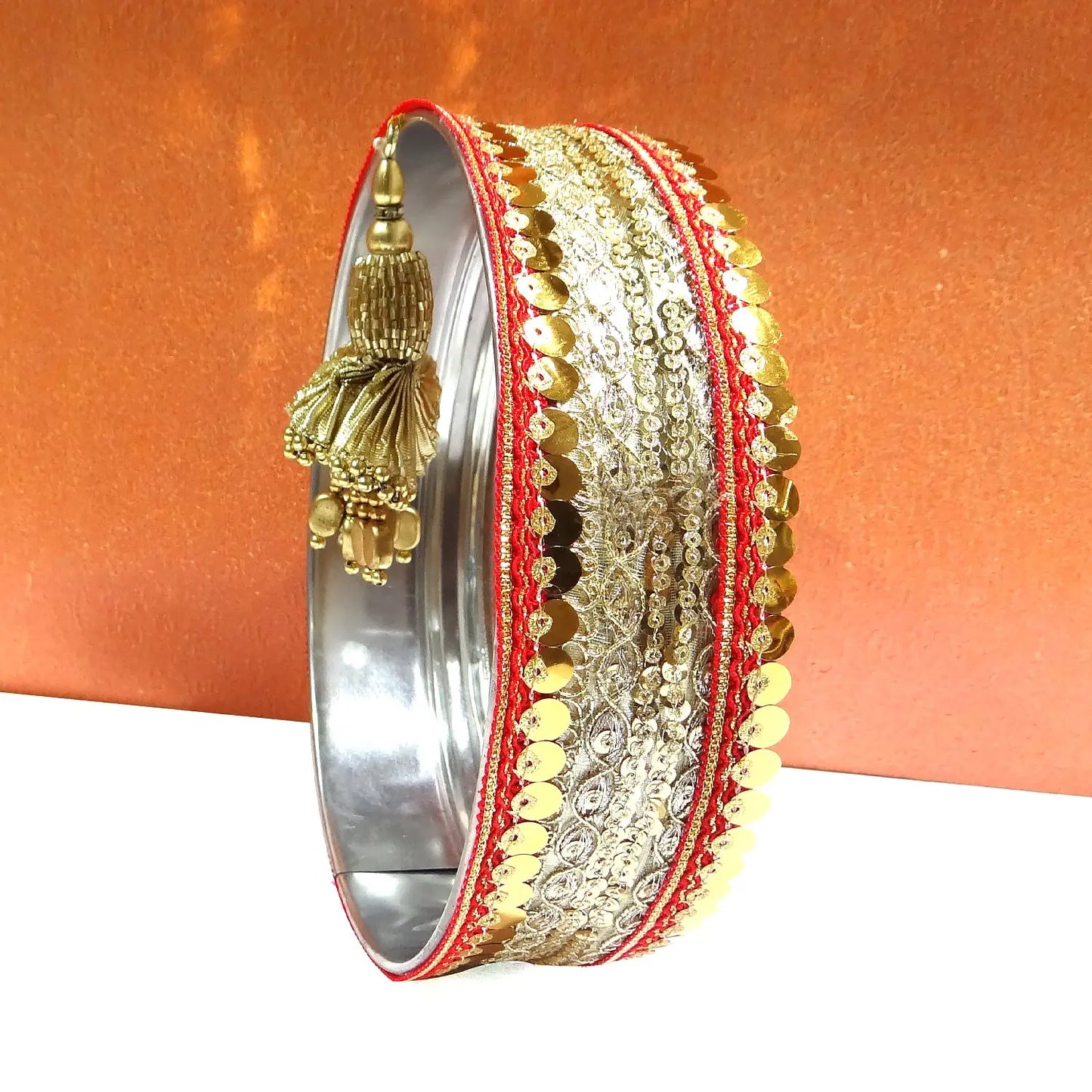 Decorative bangle with gold and red details on an orange background