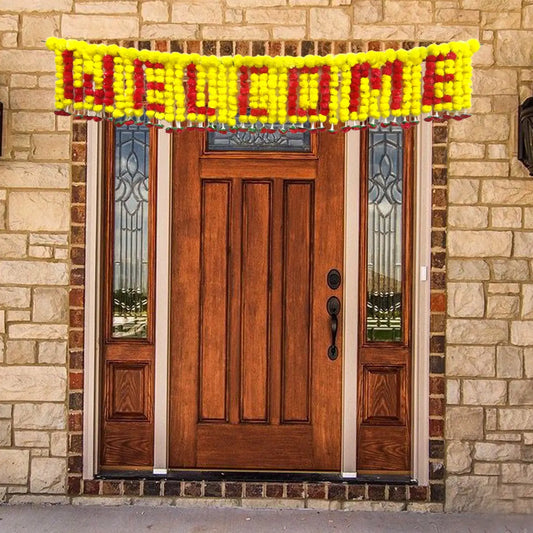 Wooden front door with a 'WELCOME' banner made of flowers on a stone wall background