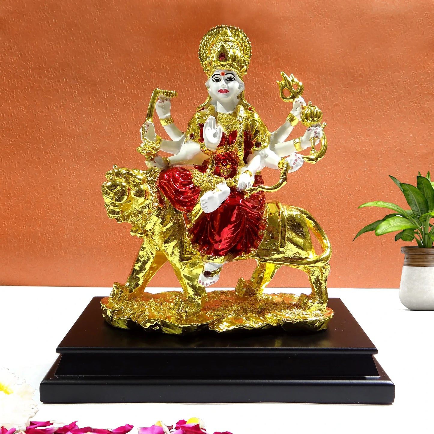 Decorative statue of a deity on a lion with gold and red colors on a white background