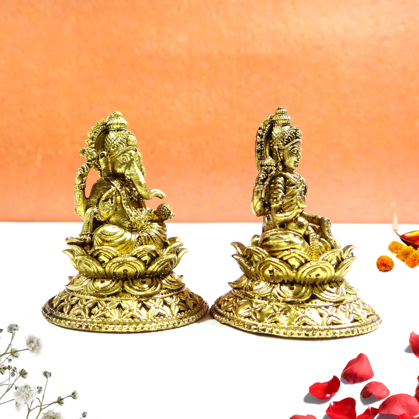 Two gold-colored statues on a white surface with an orange background