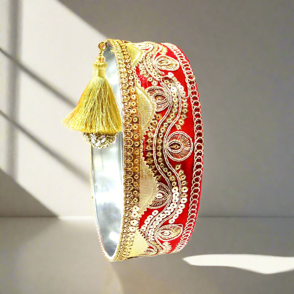 Decorative red and gold bangle with tassel on an orange background