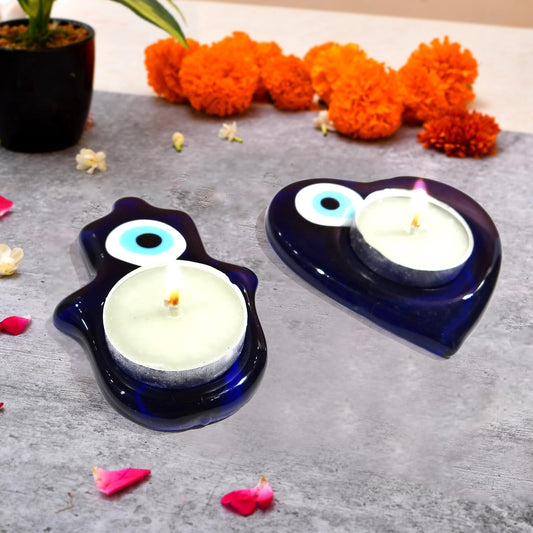 Two blue candle holders with candles on a gray surface, surrounded by decorative flowers.