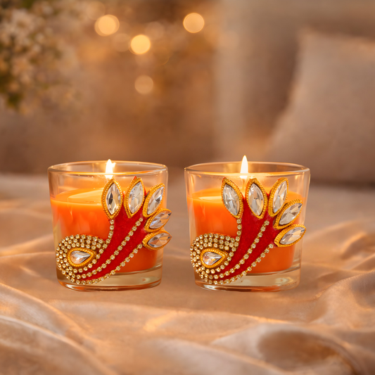Two decorative candles with peacock feather design on a soft surface with blurred background