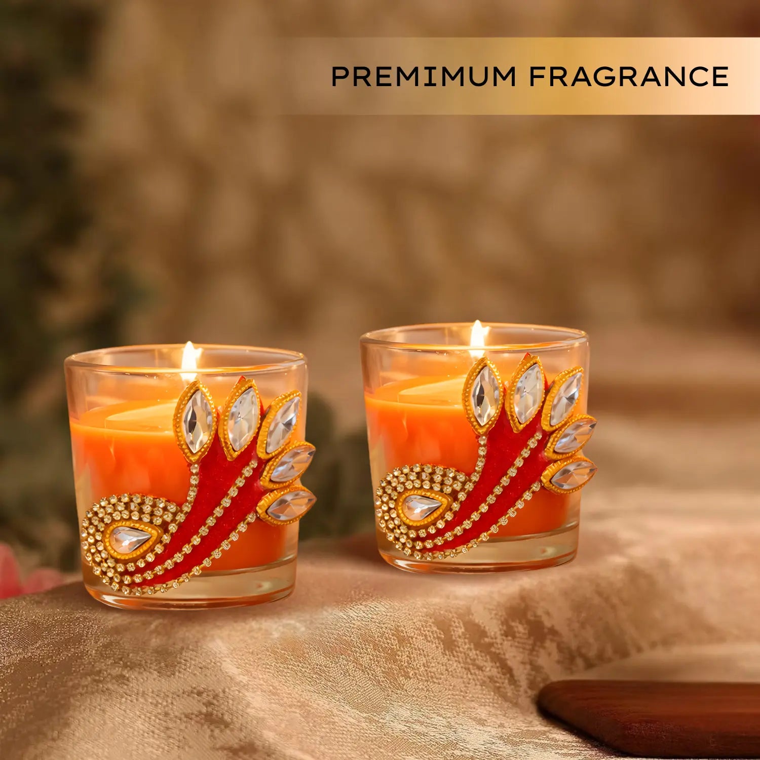 Two lit candles in decorative glass holders with a blurred background and 'PREMIUM FRAGRANCE' text.