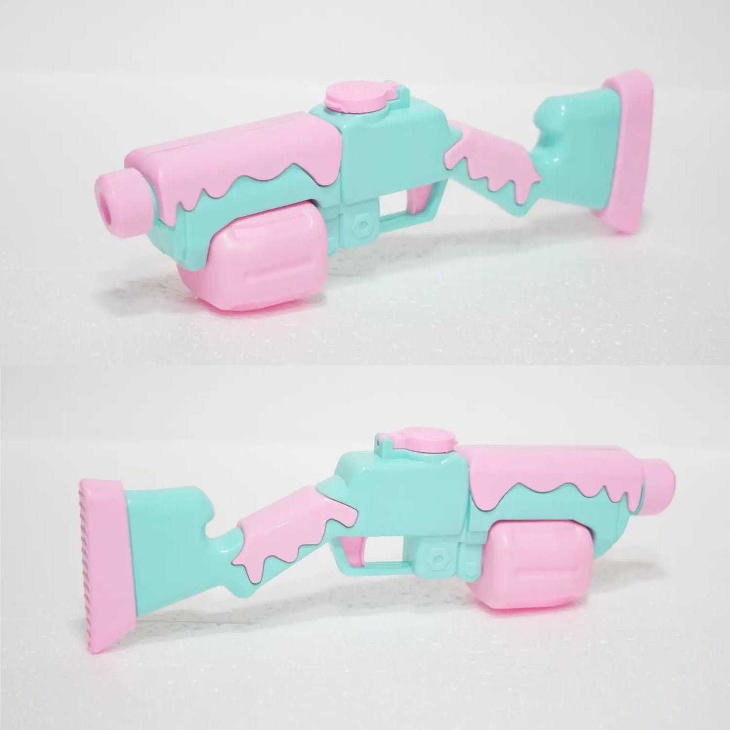Pastel pink and turquoise toy gun on a white background