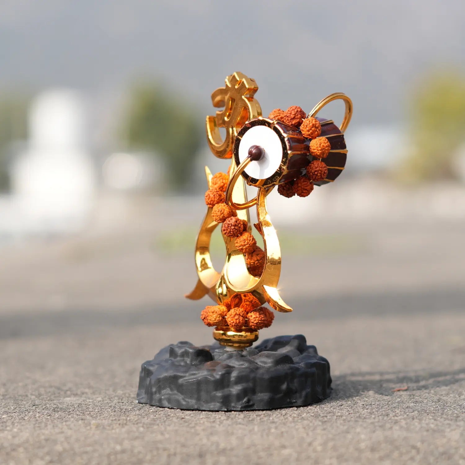 Decorative sculpture with gold and orange elements on a stone base outdoors